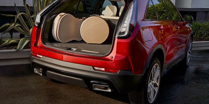 Rear view of a red Cadillac XT4 with the liftgate open, revealing a spacious cargo area packed with circular luggage.