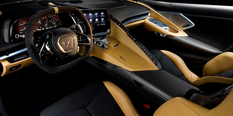 Interior view of a Chevrolet Corvette featuring a tan and black leather cabin with a driver-focused dashboard and touchscreen display.