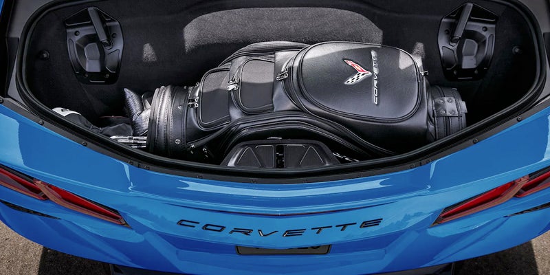 Open rear trunk of a blue Chevrolet Corvette containing a black golf bag with a Corvette logo.