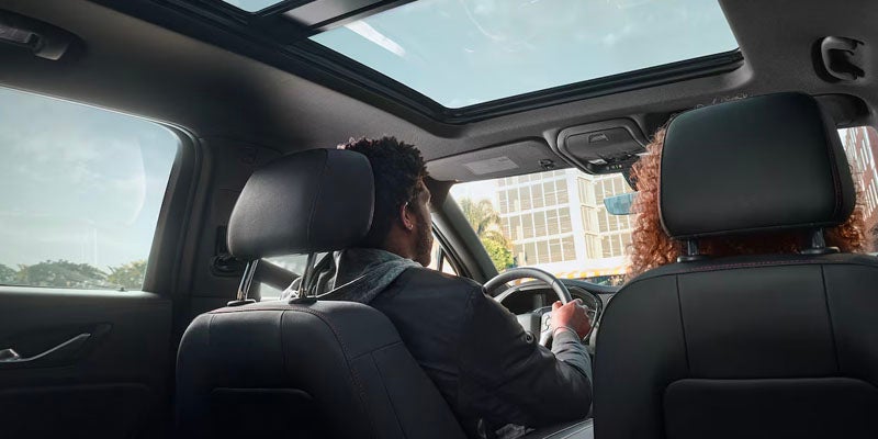 Interior view of a 2025 Chevrolet Blazer showing two passengers and a panoramic sunroof letting in natural light