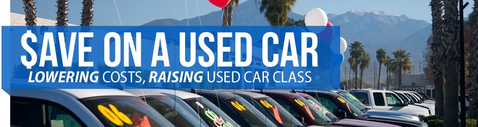 Banner with used cars for sale, SAVE ON A USED CAR LOWERING COSTS, RAISING USED CAR CLASS written on it.